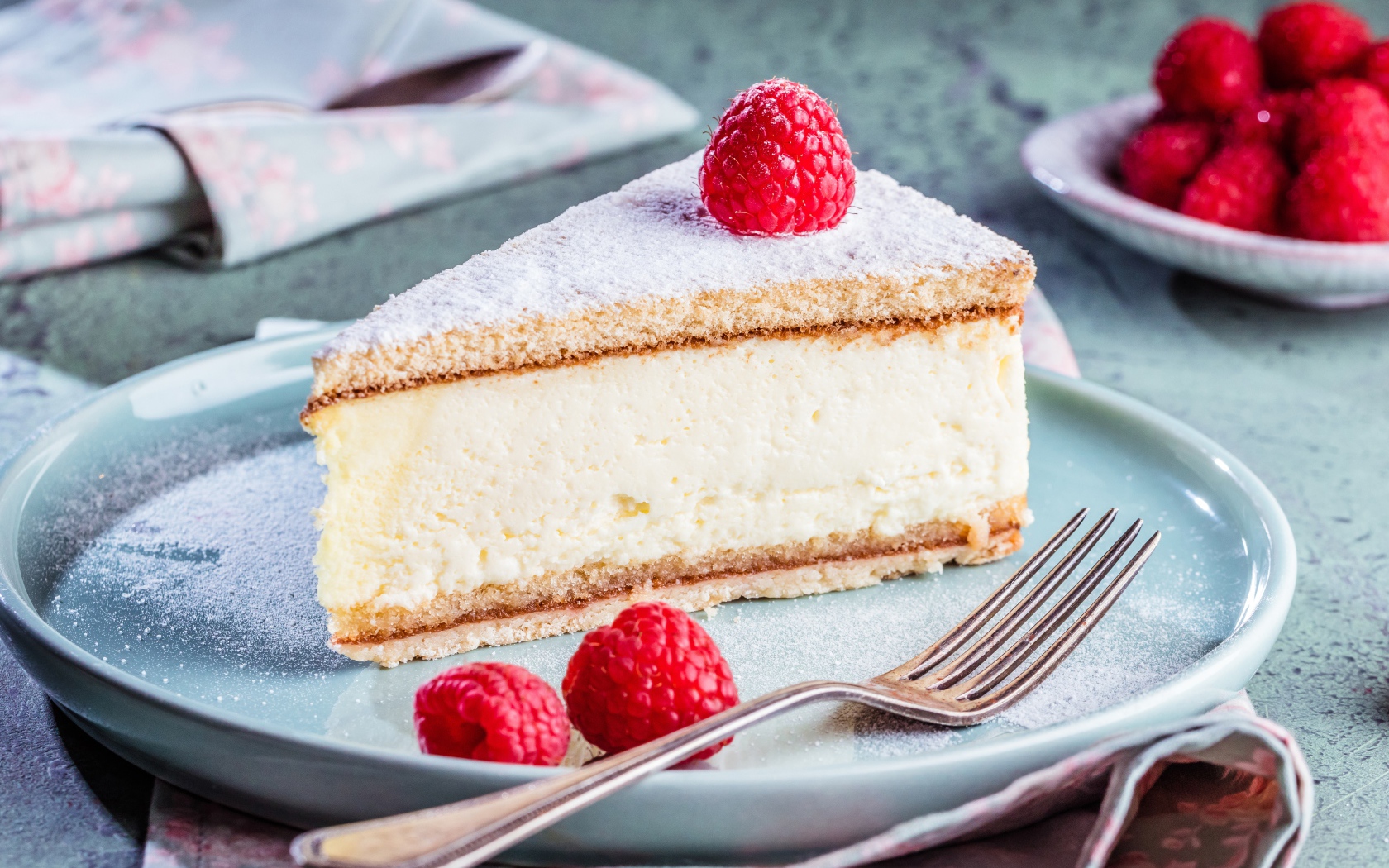 Чизкейк с сахарной пудрой и ягодами малины на тарелке