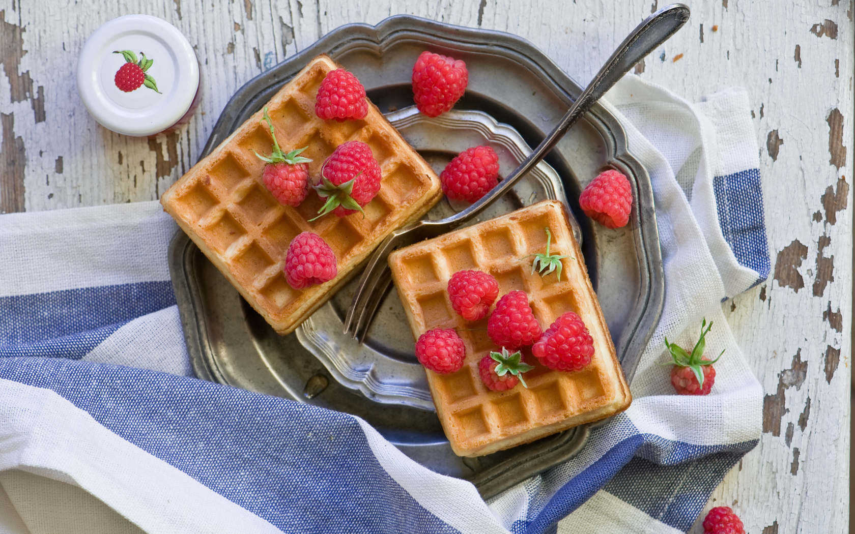 Сладкие вафли с ягодами малины на столе 