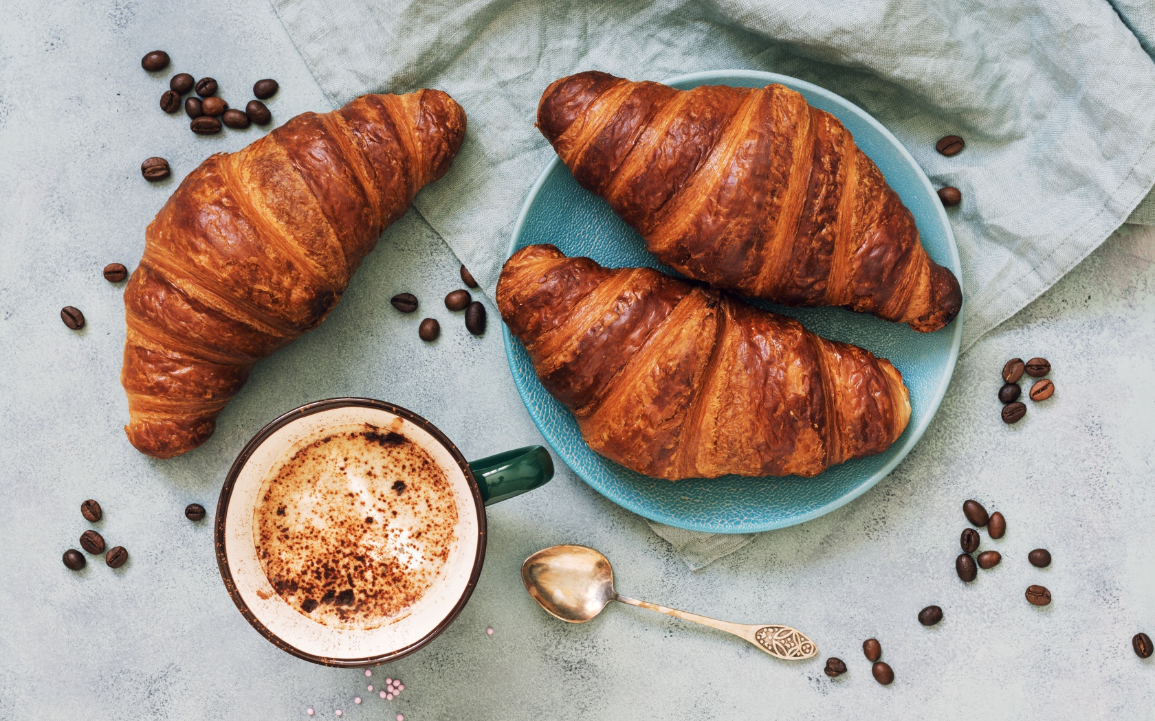Три круассана на столе с чашкой кофе