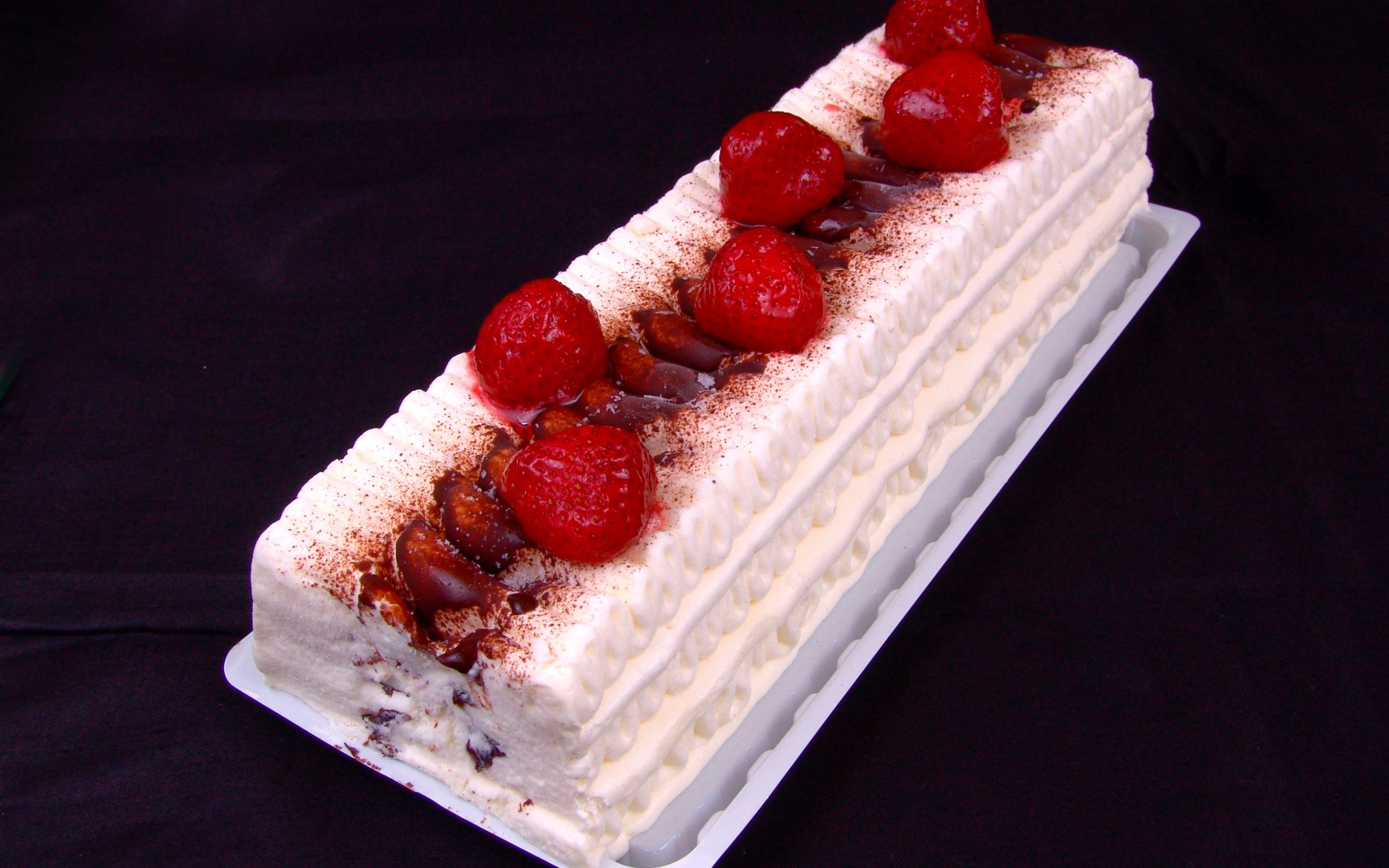 Белый торт с клубникой на черном фоне