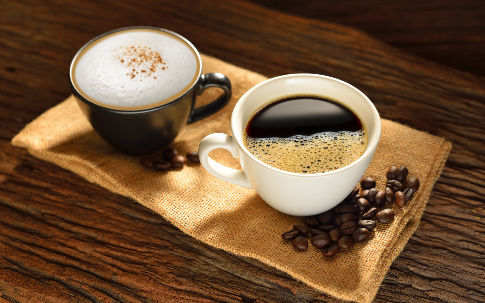 Чашка кофе и чашка капучино на столе с кофейными зернами