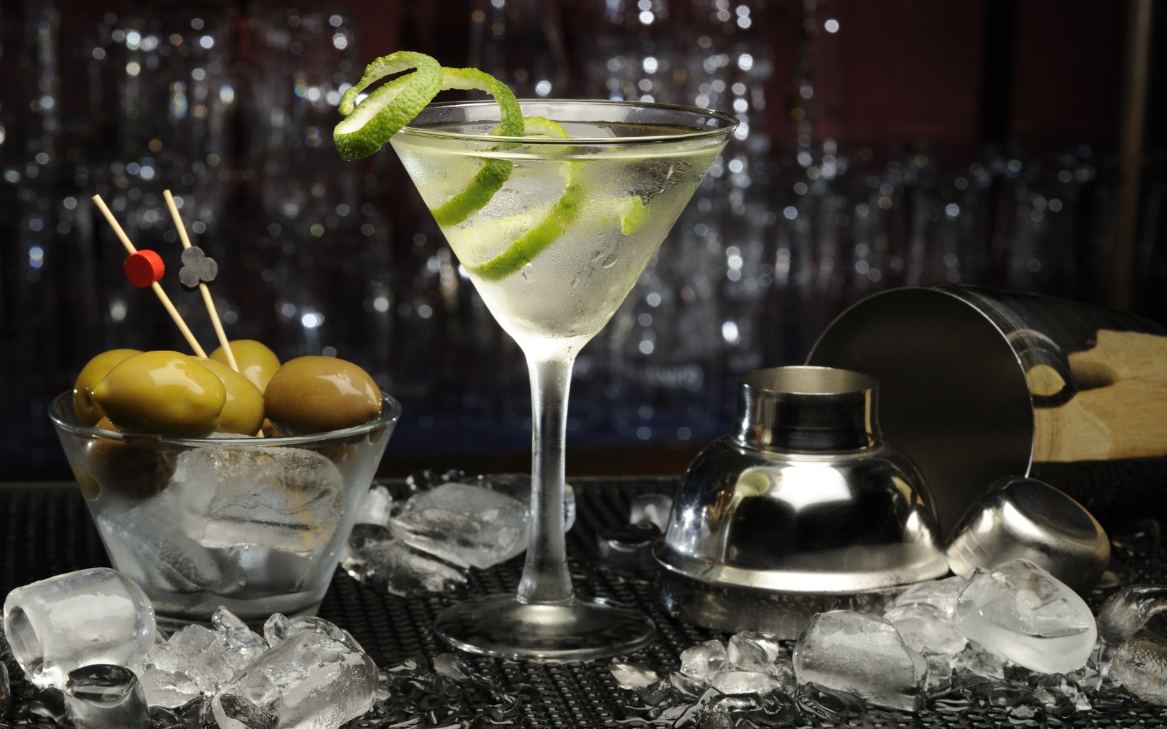 Коктейль с лаймом на столе с оливками и кубиками льда