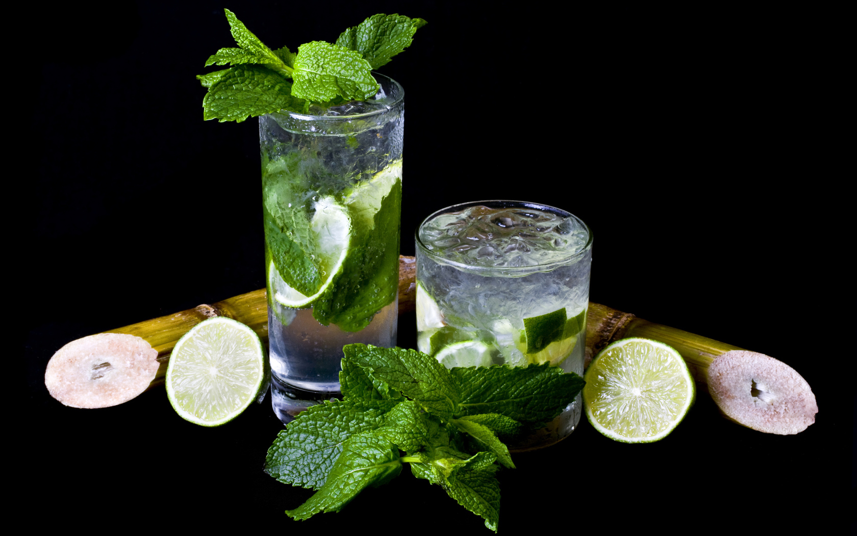 Напиток мохито в стаканах с лаймом и листьями мяты на черном фоне
