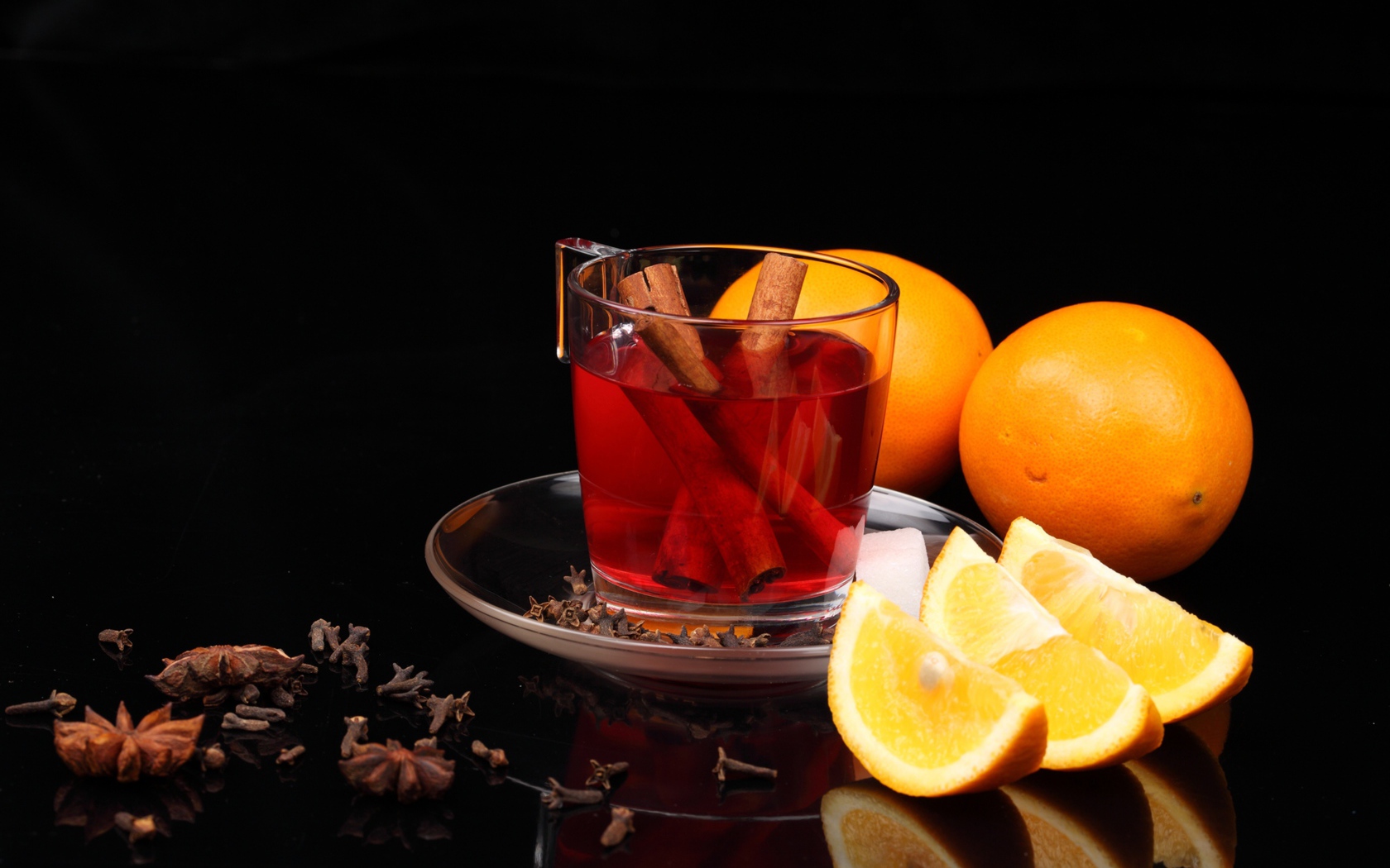 Чай с корицей и кусочками апельсина на черном фоне