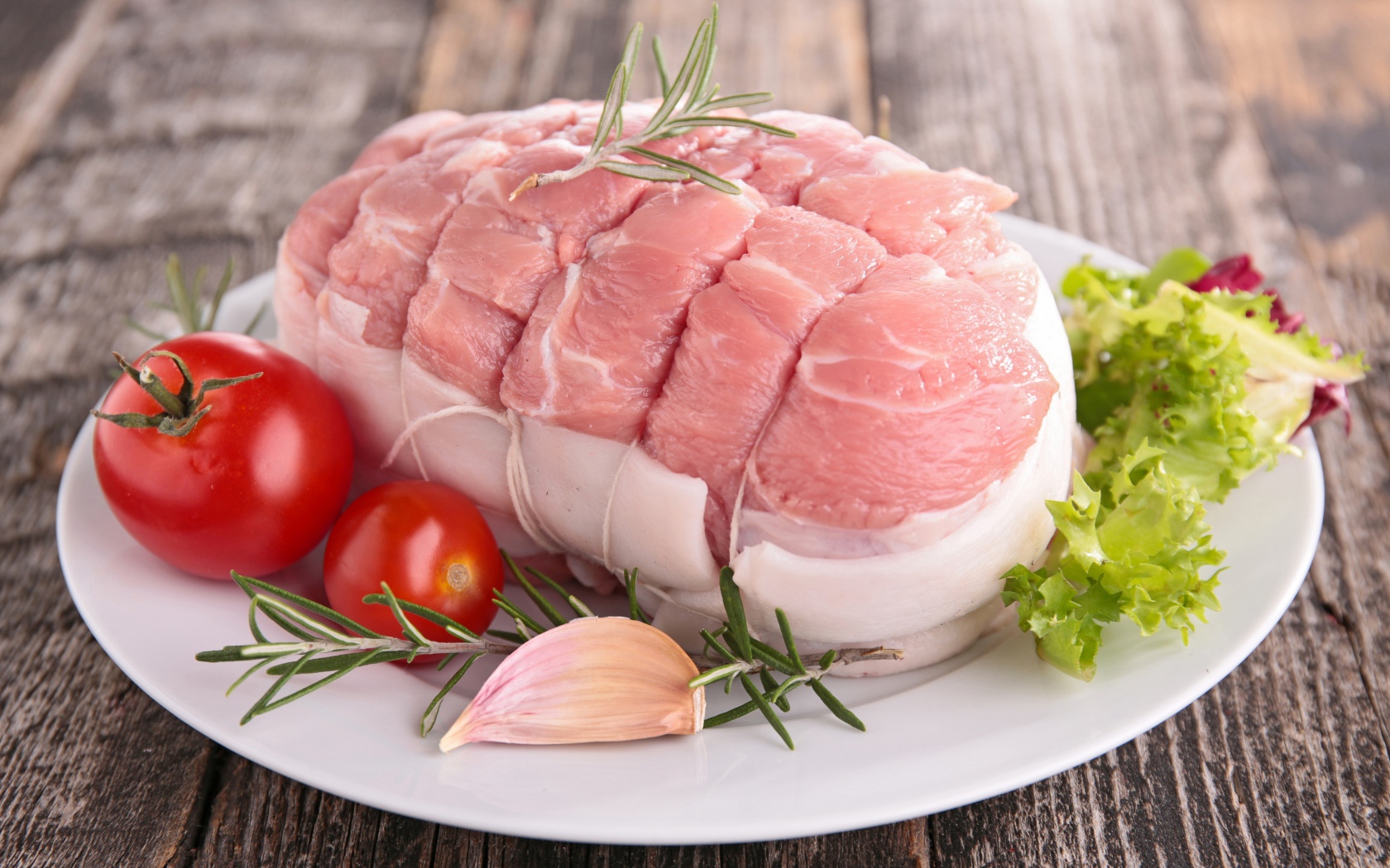 Кусок свежего мяса со свежими помидорами, чесноком и листьями салата