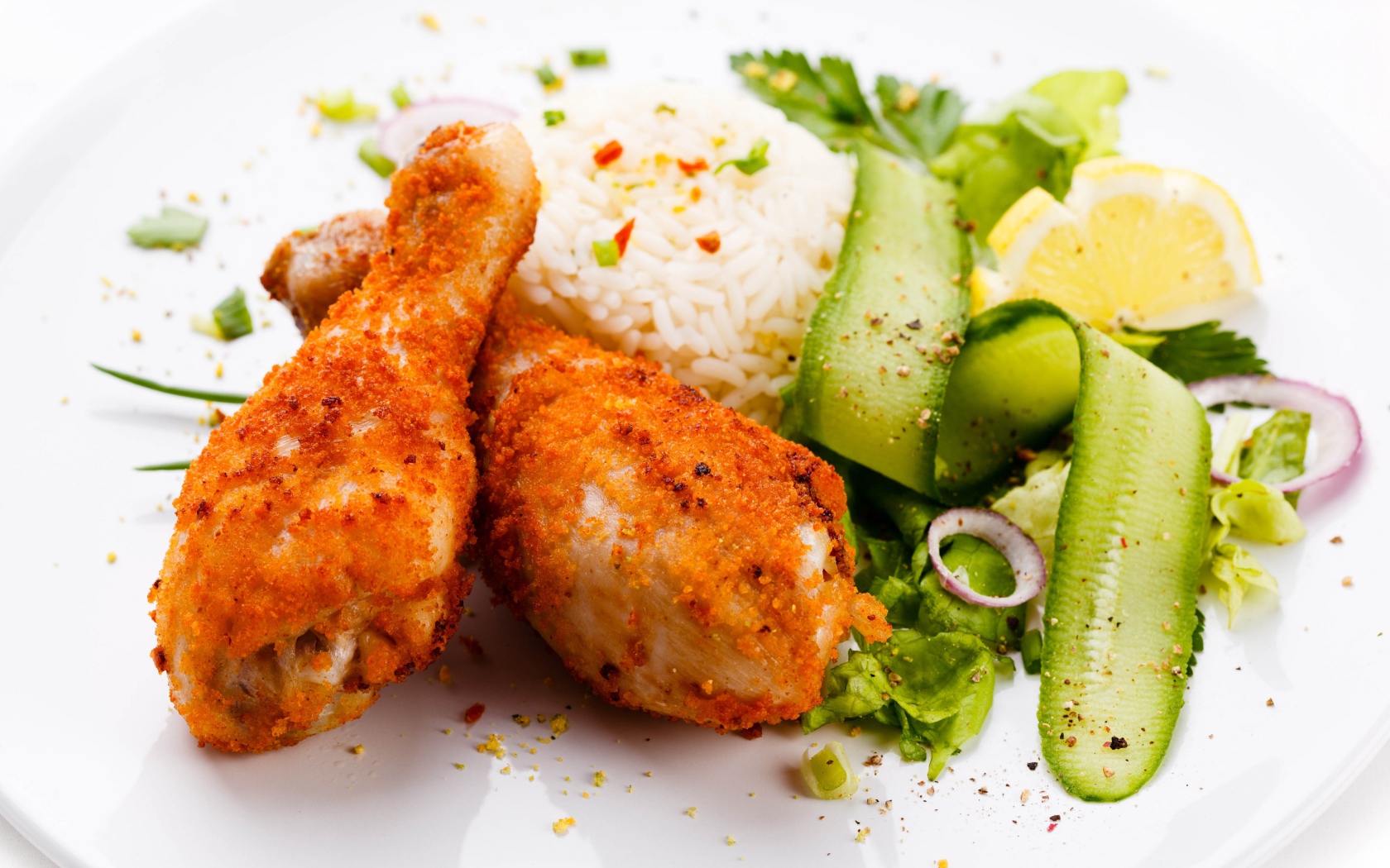 Куриные ножки с рисом и салатом на белой тарелке