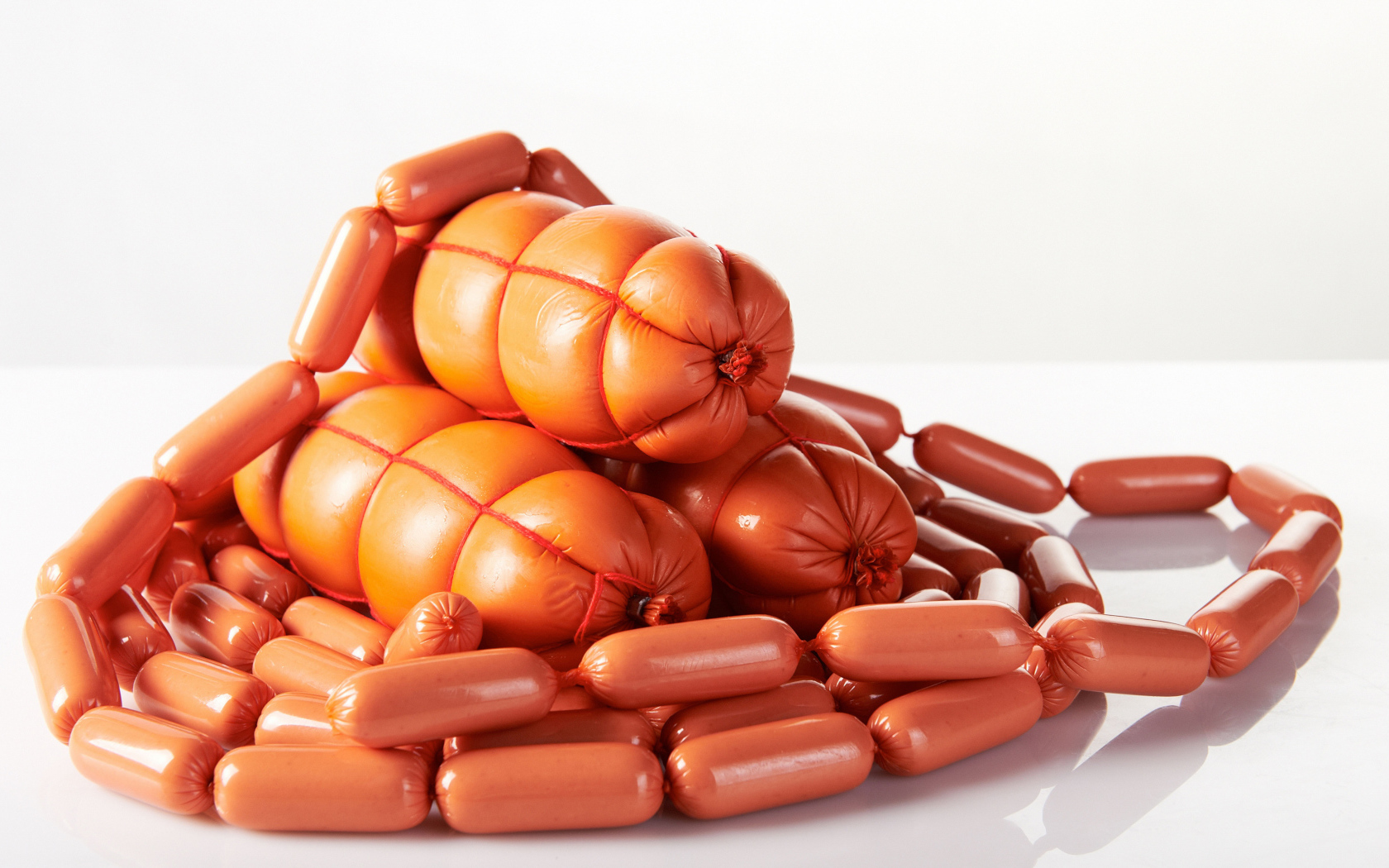 Свежие сосиски и колбаса на белом фоне