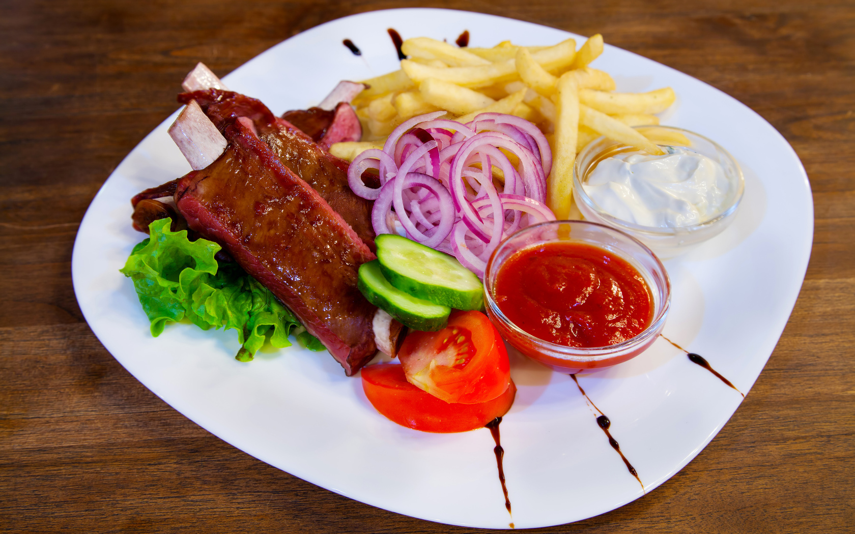 Мясо с овощами и картофелем фри на большой белой тарелке с соусом