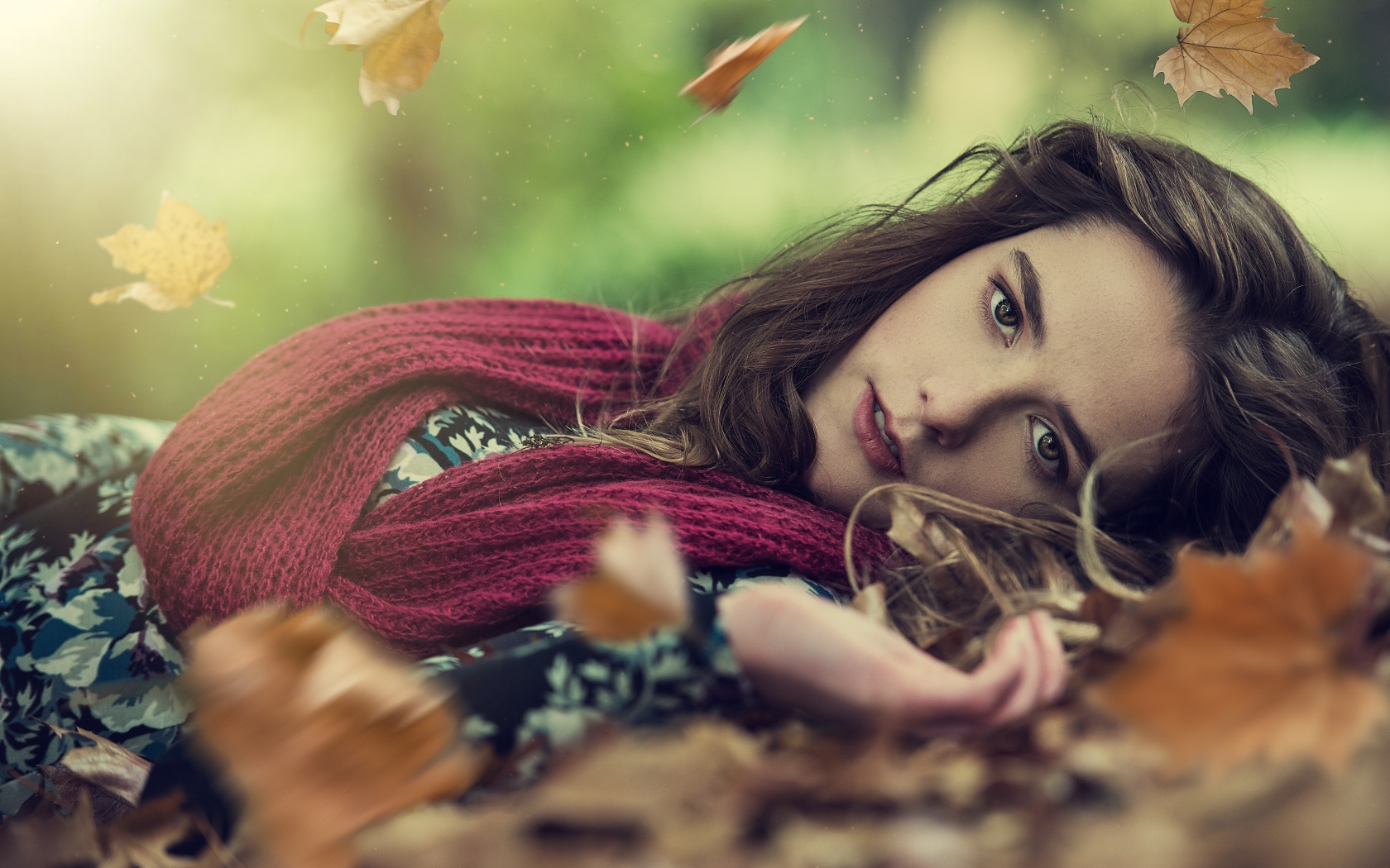 Красивая шатенка в красном шарфе лежит на сухой листве