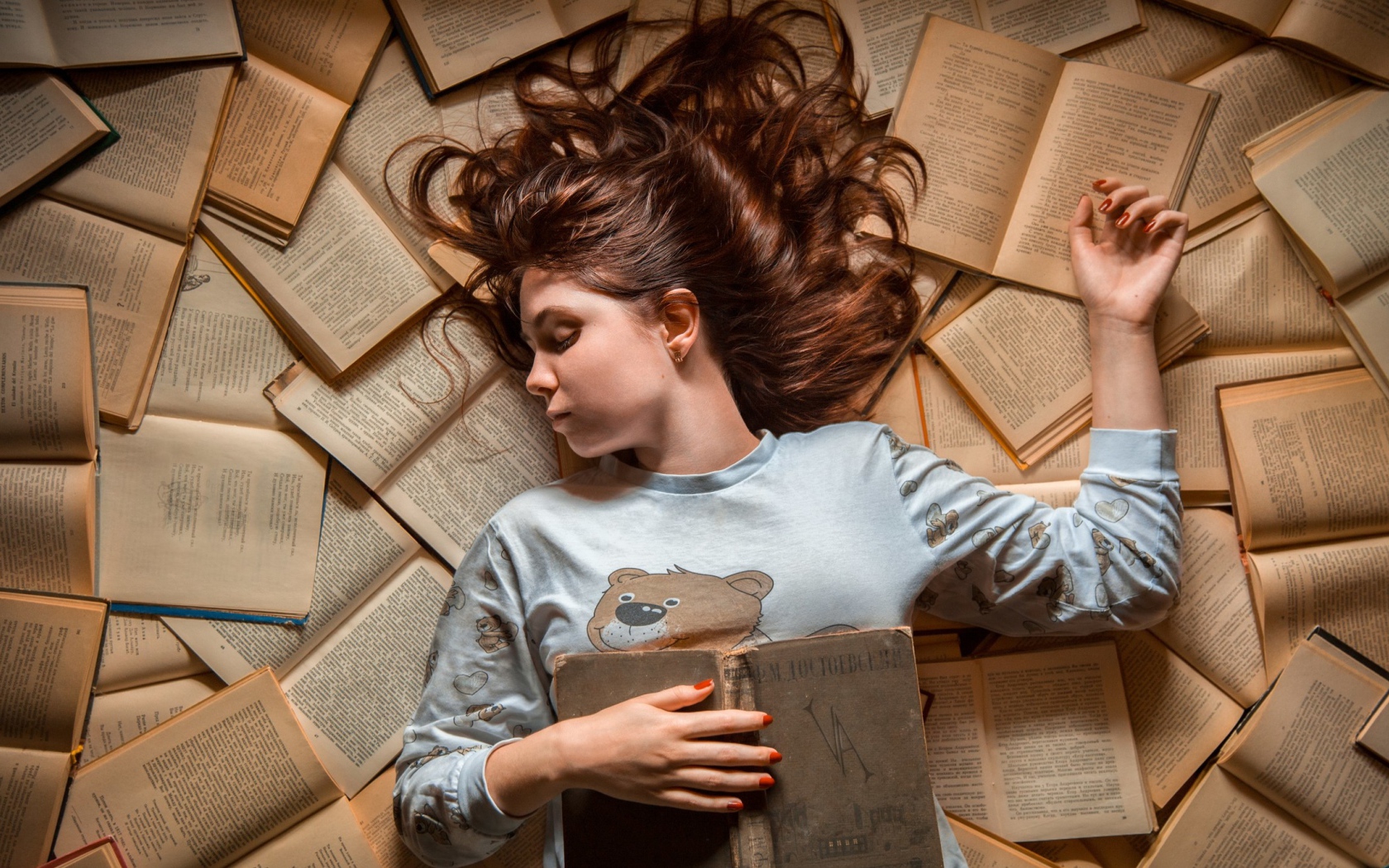 Молодая девушка спит на книгах
