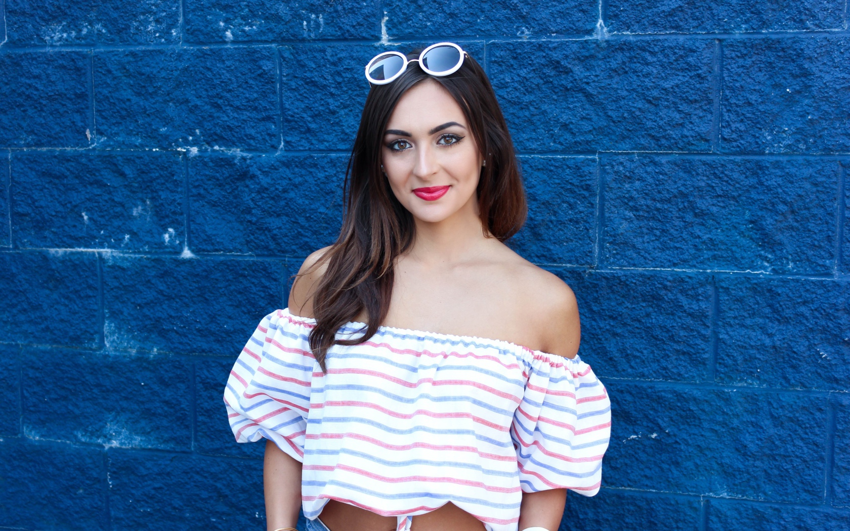 Красивая улыбающаяся девушка на фоне синей стены