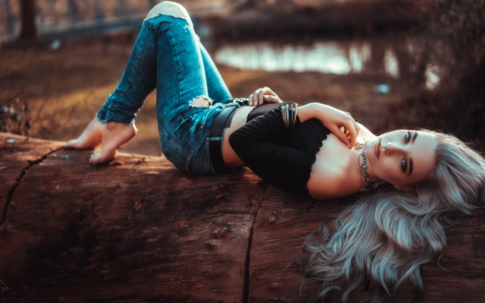 Красивая молодая блондинка лежит на сухом дереве