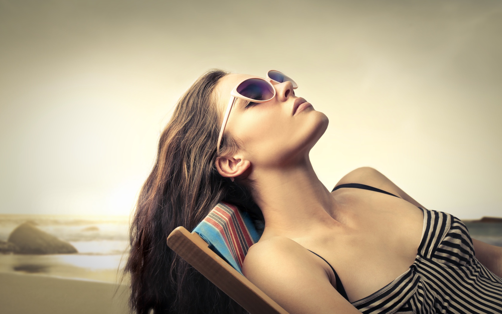 Красивая молодая девушка в очках лежит на шезлонге