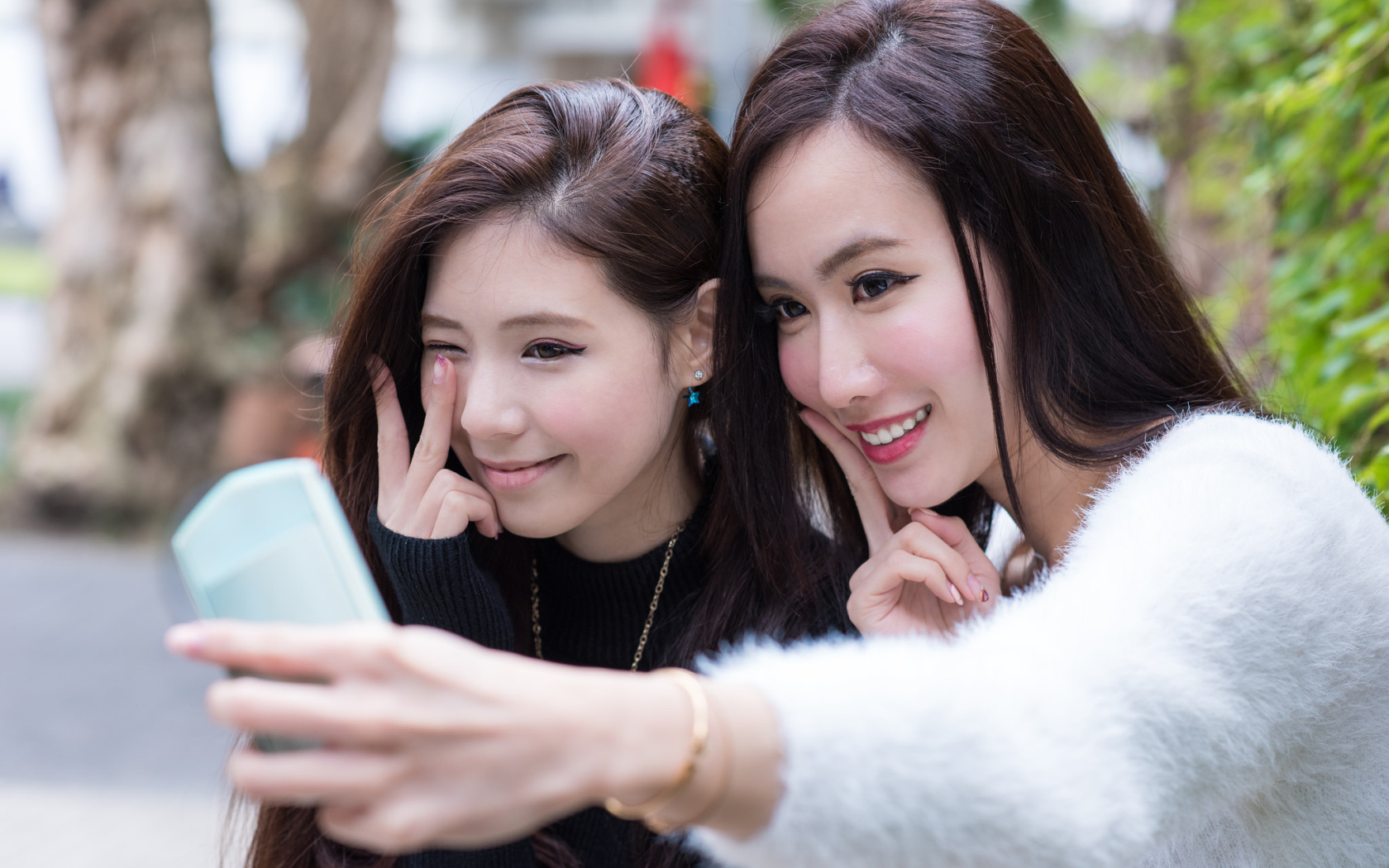Две девушки азиатки делают селфи