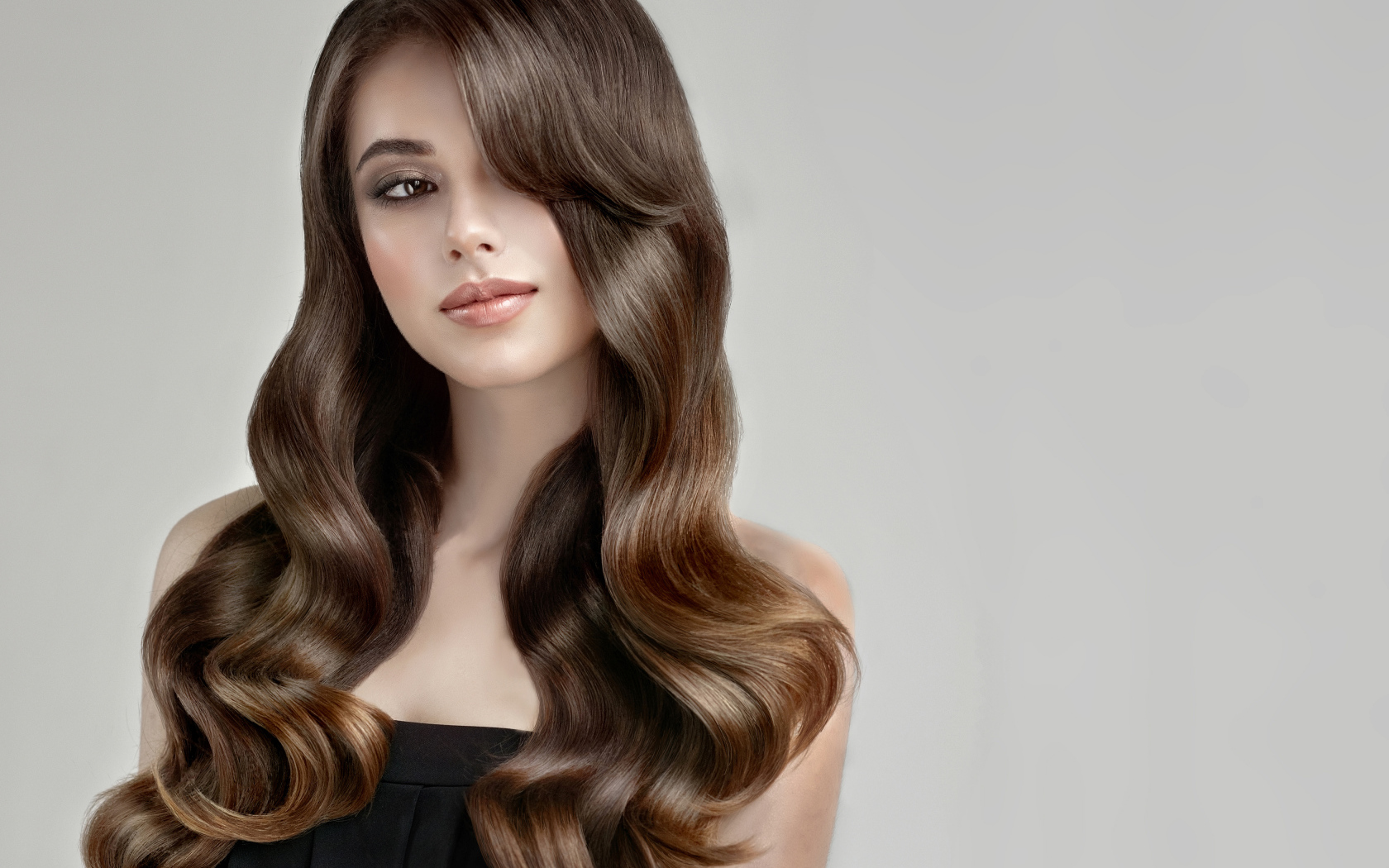 Молодая девушка с красивыми длинными волосами на сером фоне