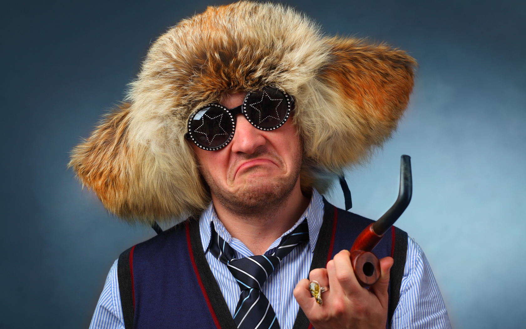 Мужчина в меховой шапке в модных очках с трубкой в руке