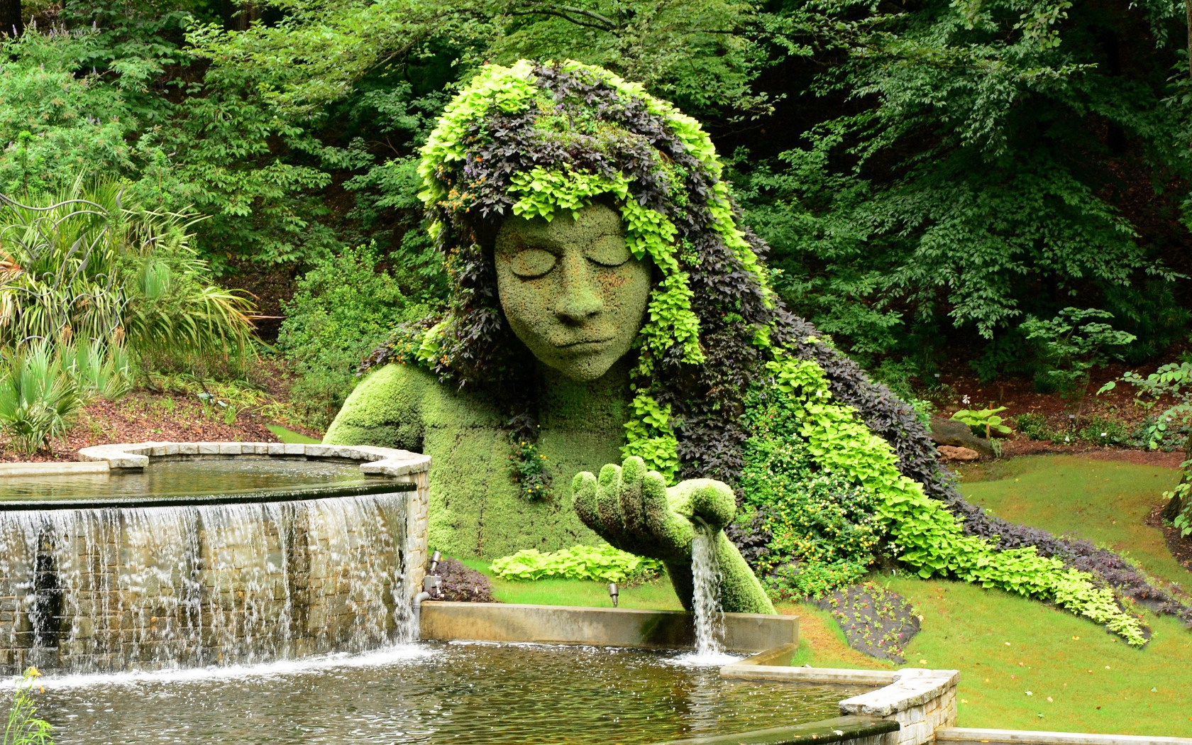 Красивый водопад в парке со скульптурой 