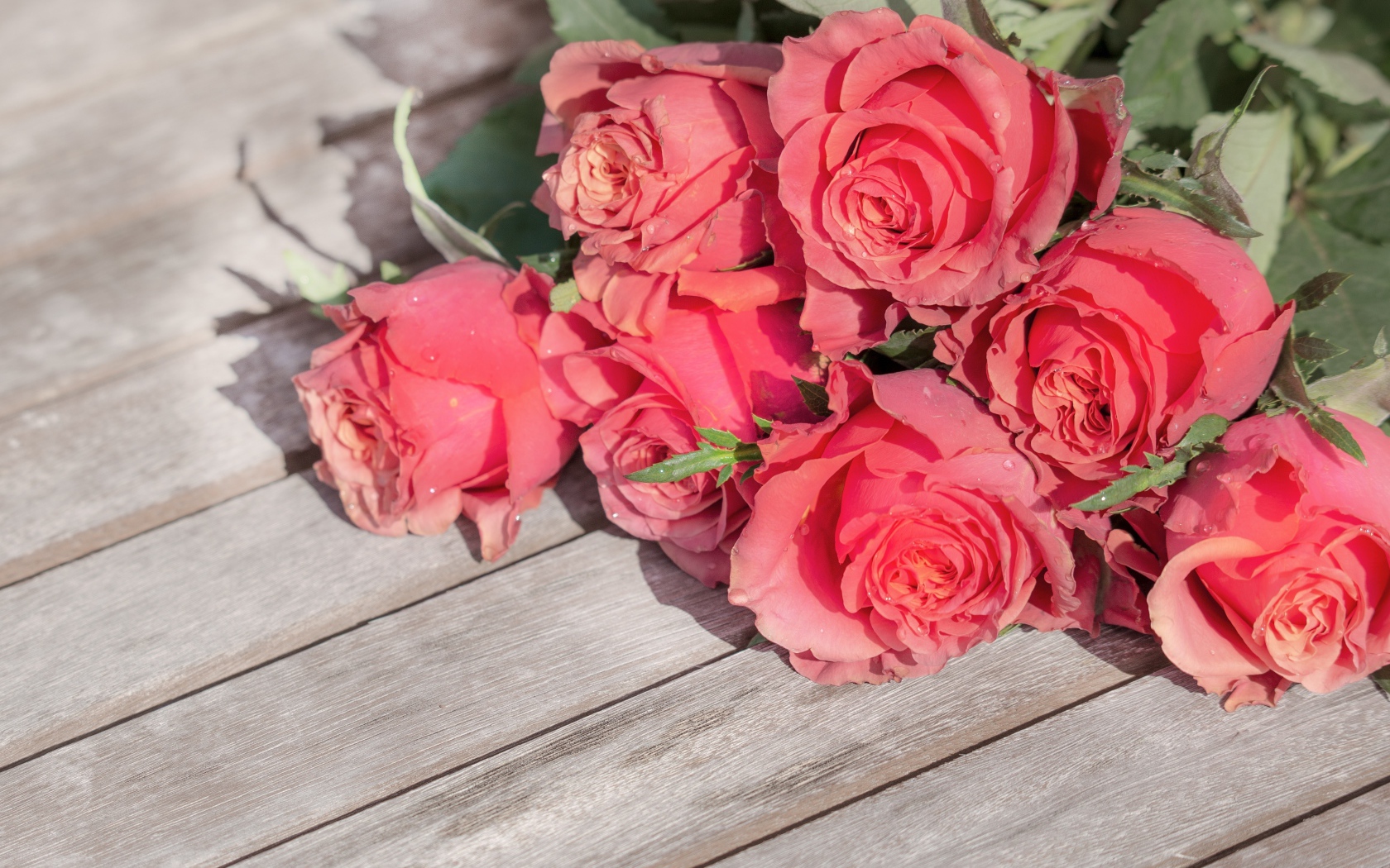 Букет розовых роз лежит на деревянной поверхности