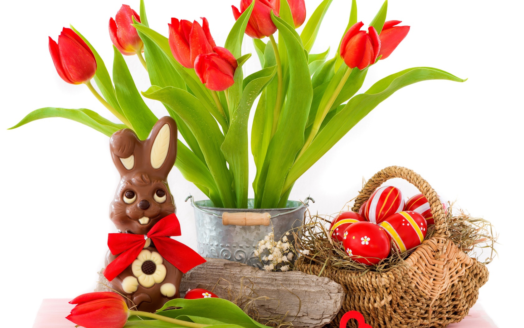 Букет красных тюльпанов на столе с шоколадным кроликом и крашеными яйцами на Пасху