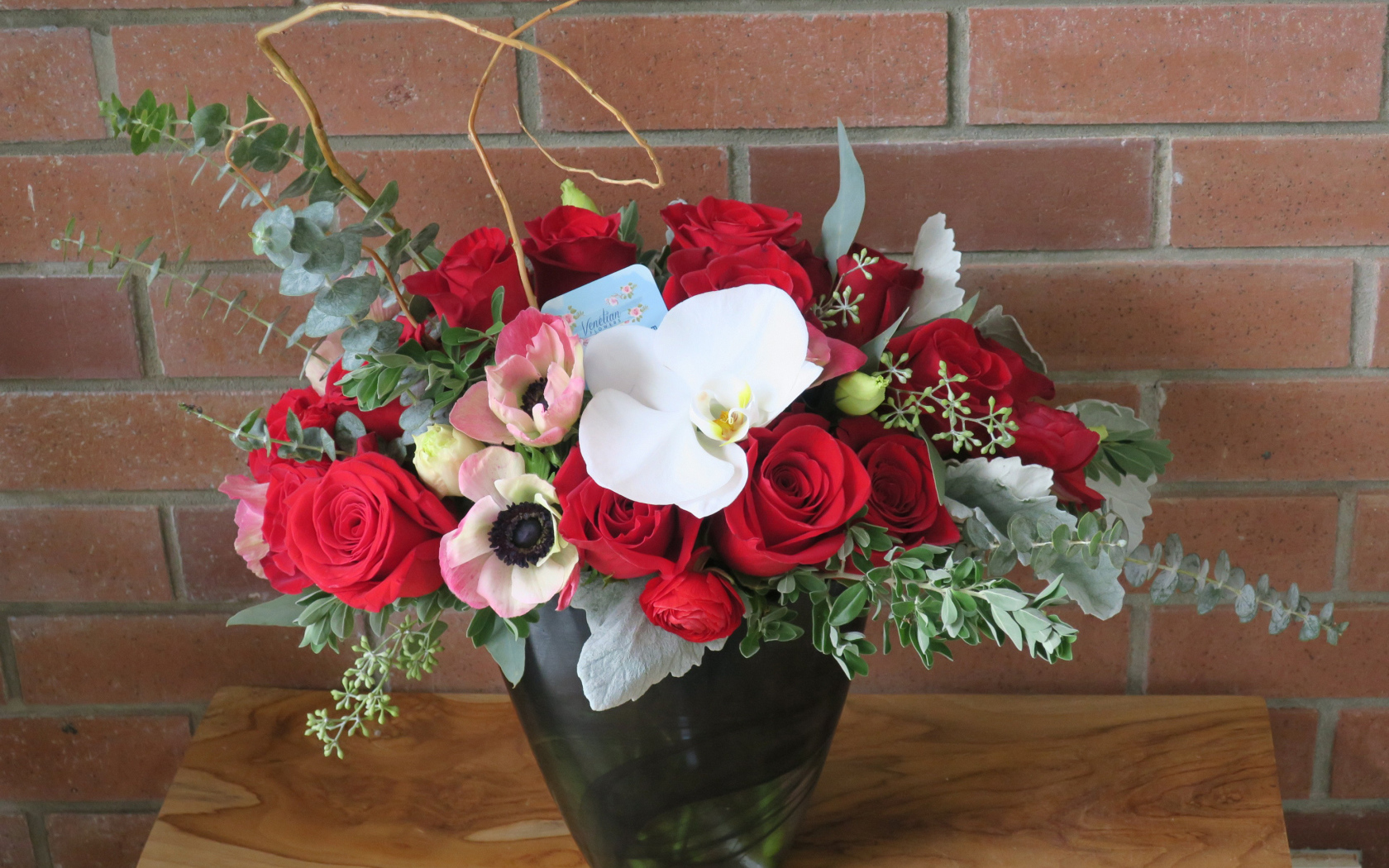 Букет с цветами анемоны, розы и орхидеи у стены 