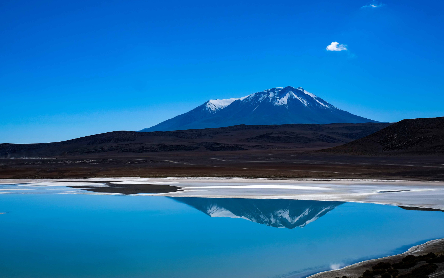 Гора отражается в воде на фоне голубого неба
