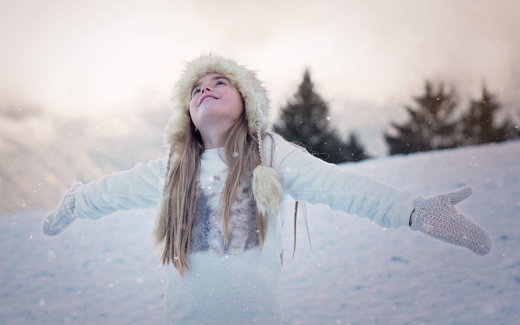 Девочка в белой шапке радуется снегу