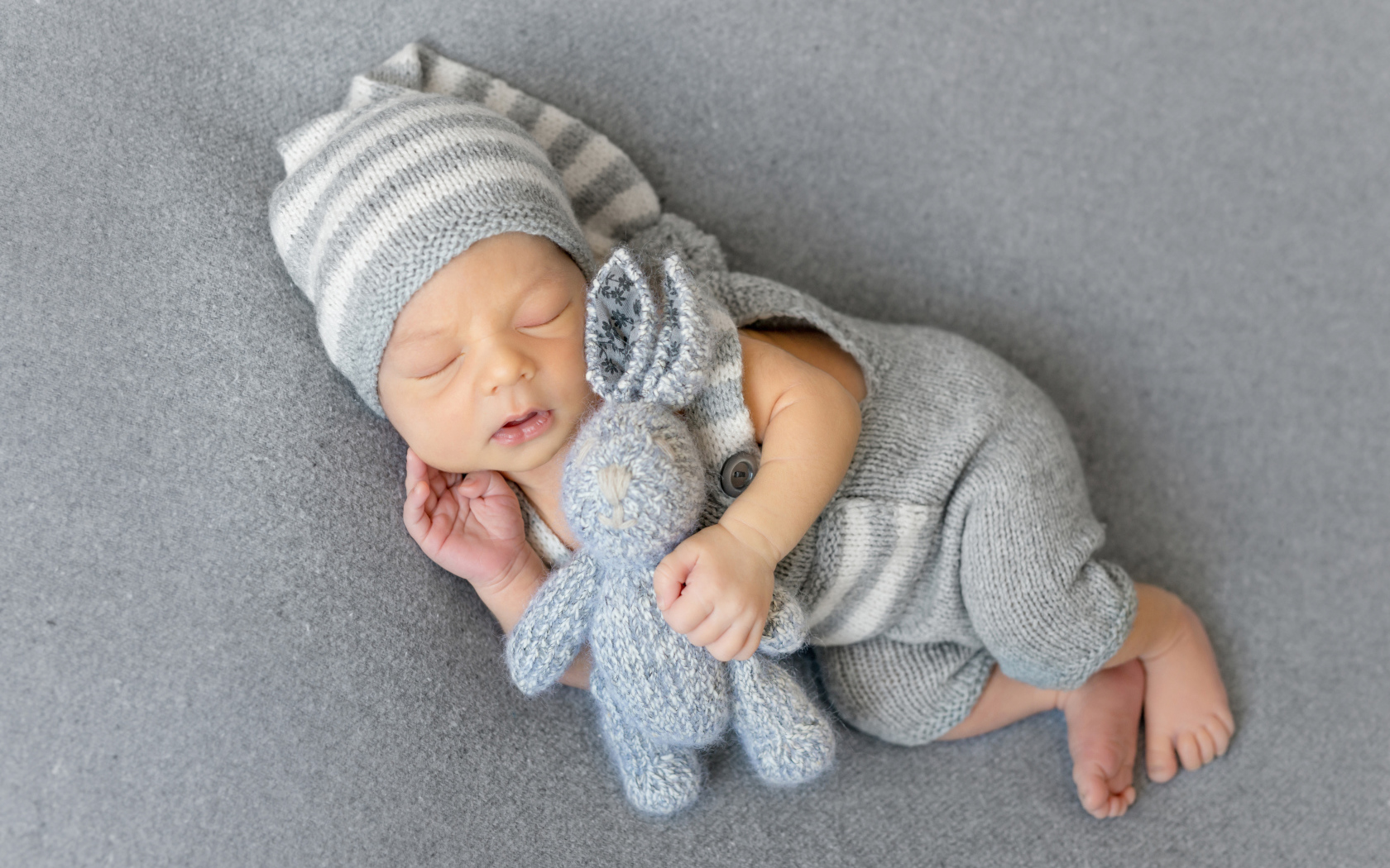 Спящий младенец с серым вязаным зайцем