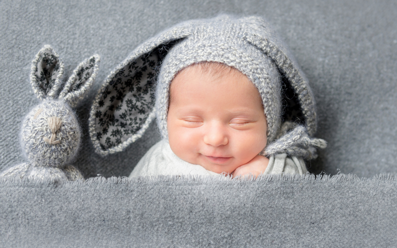 Маленький грудной ребенок в серой шапке с ушками