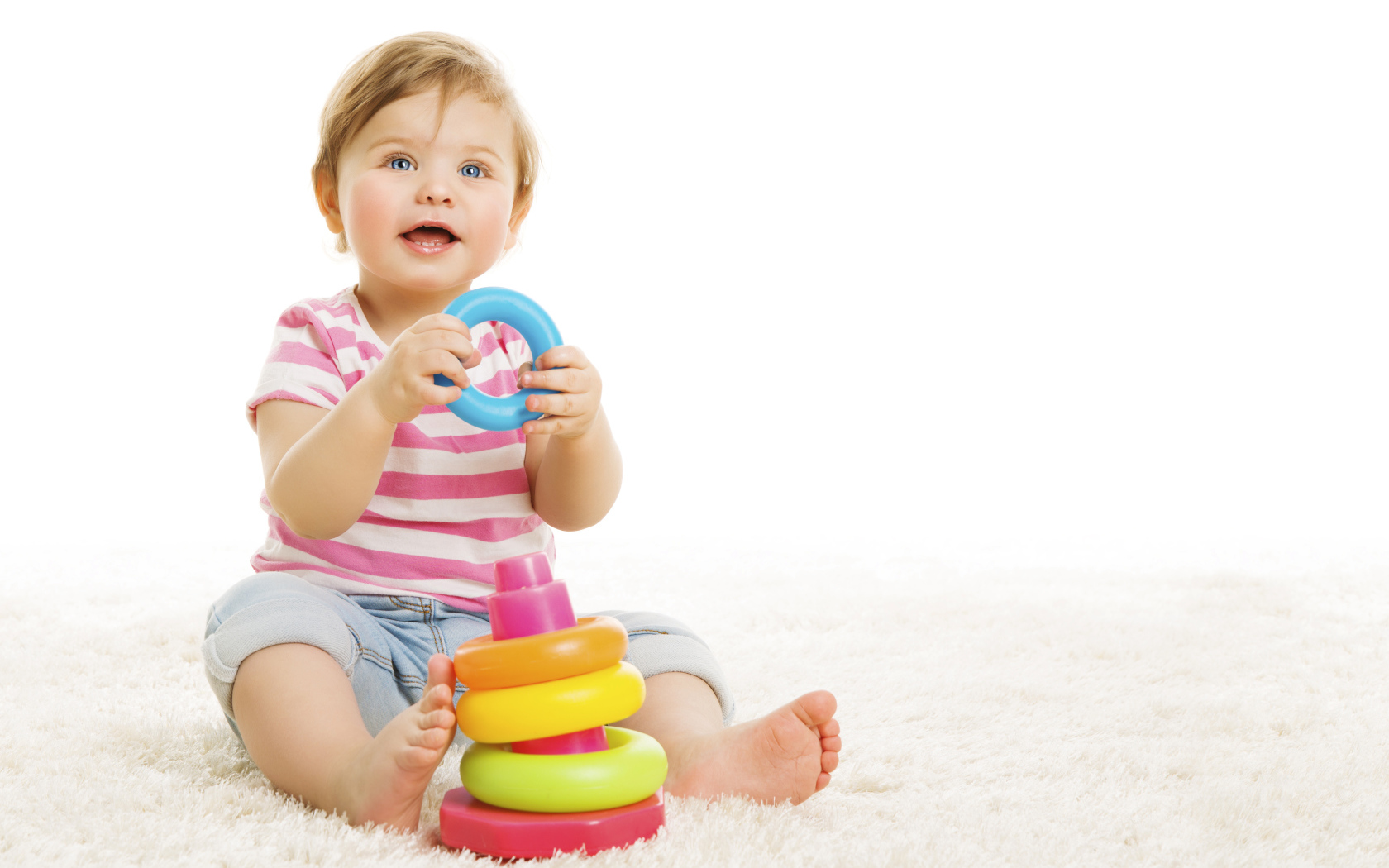 Голубоглазый маленький мальчик с игрушкой на белом фоне