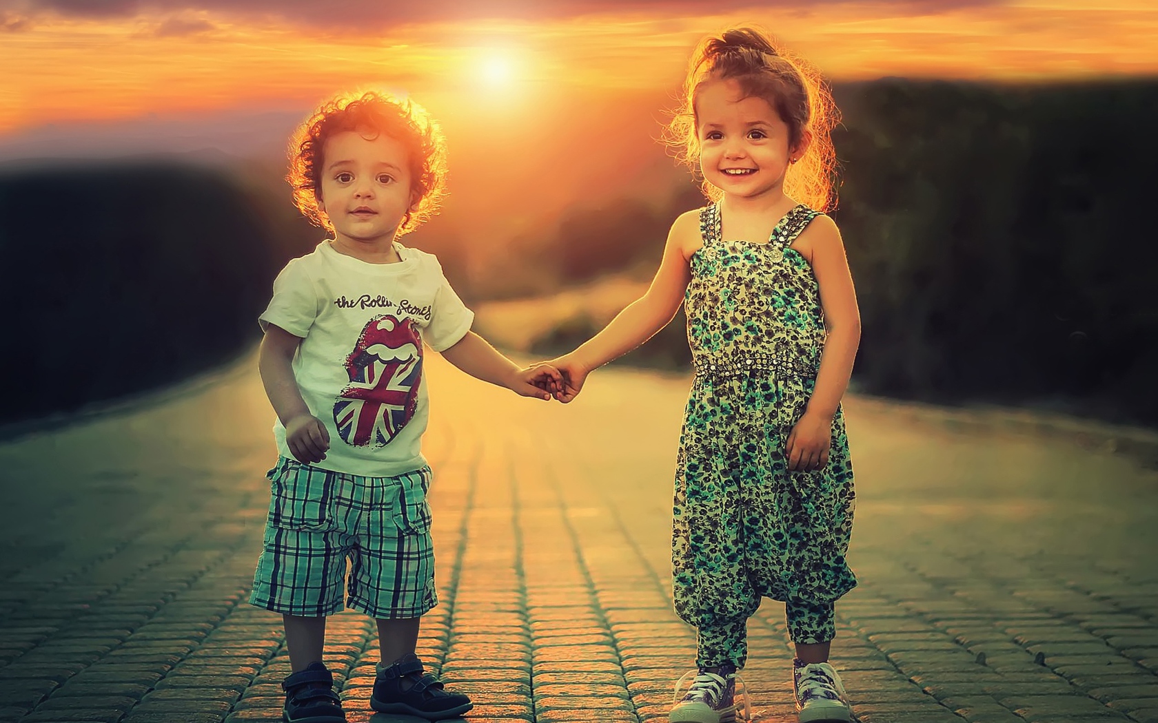 Счастливые мальчик и девочка на дороге на фоне заката