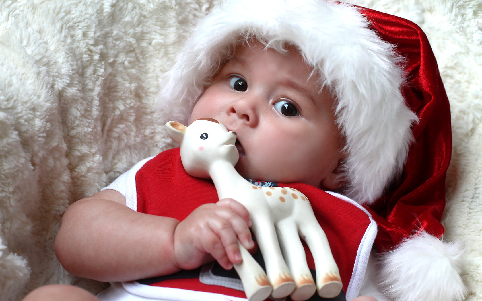 Маленький ребенок в новогодней шапке с игрушкой в руке