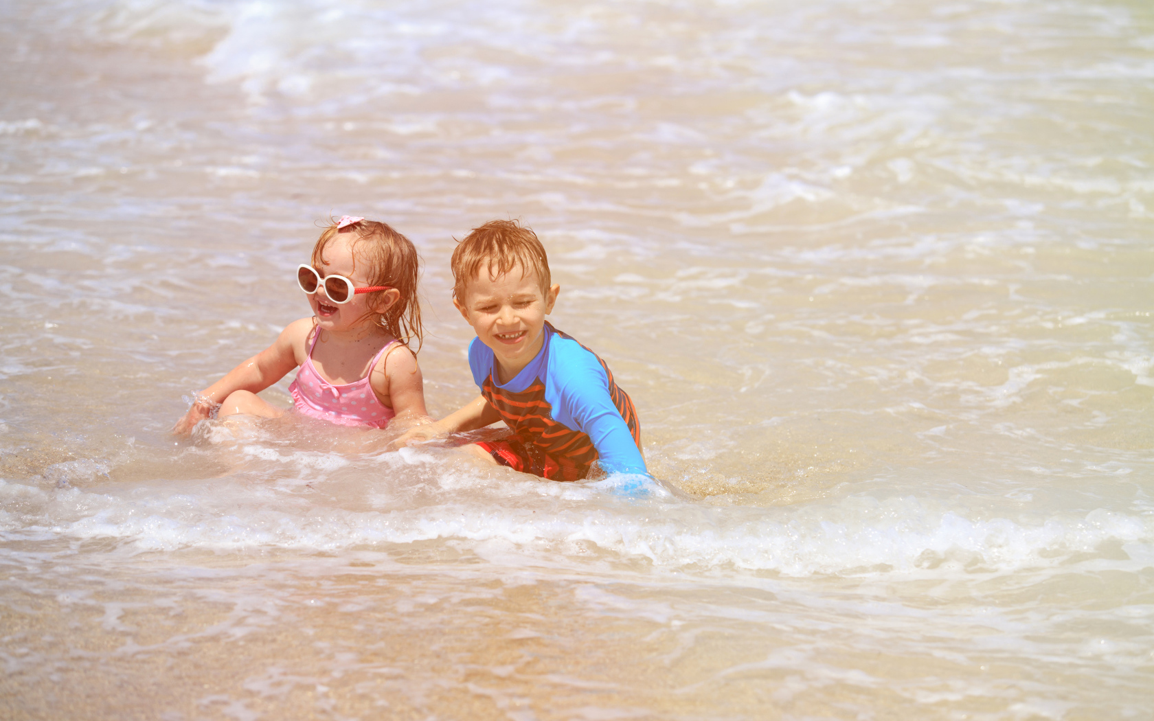 Маленькие мальчик и девочка купаются в море 