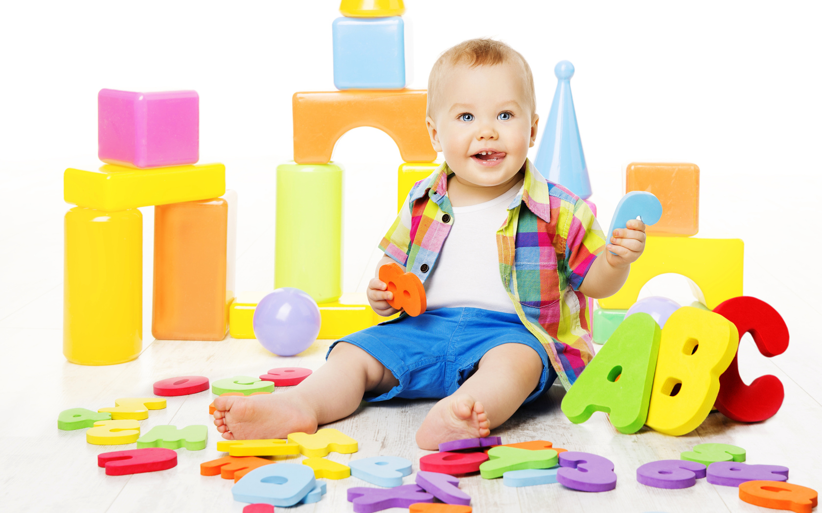 Маленький мальчик играет с разноцветными игрушками 