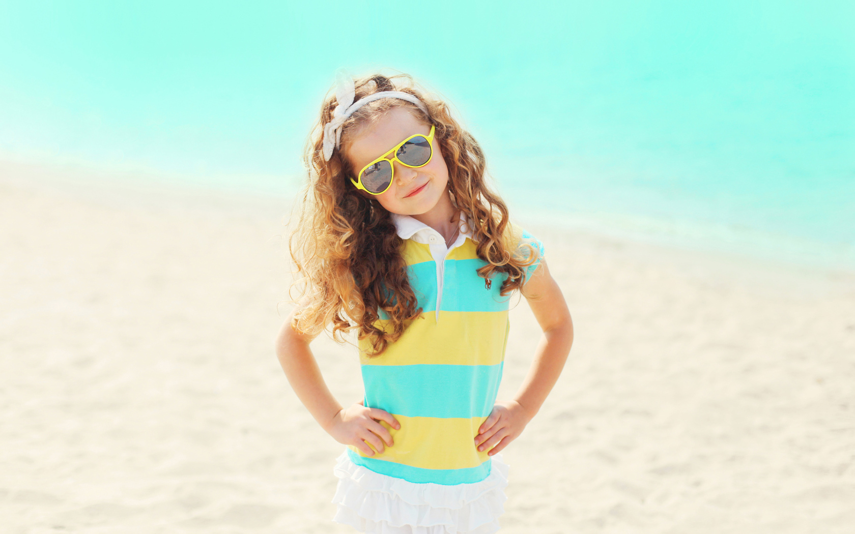 Маленькая модная девочка в солнечных очках на пляже