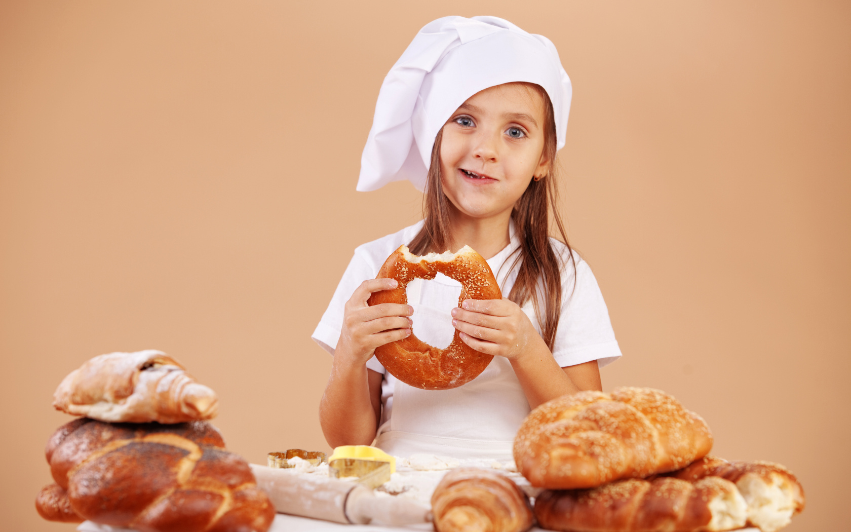 Маленькая девочка в костюме повара и свежей выпечкой