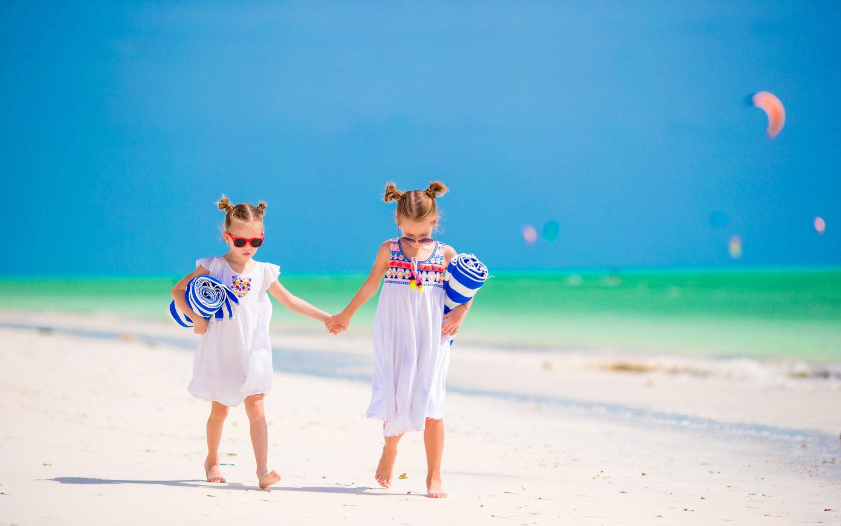 Две маленькие девочки идут по песку