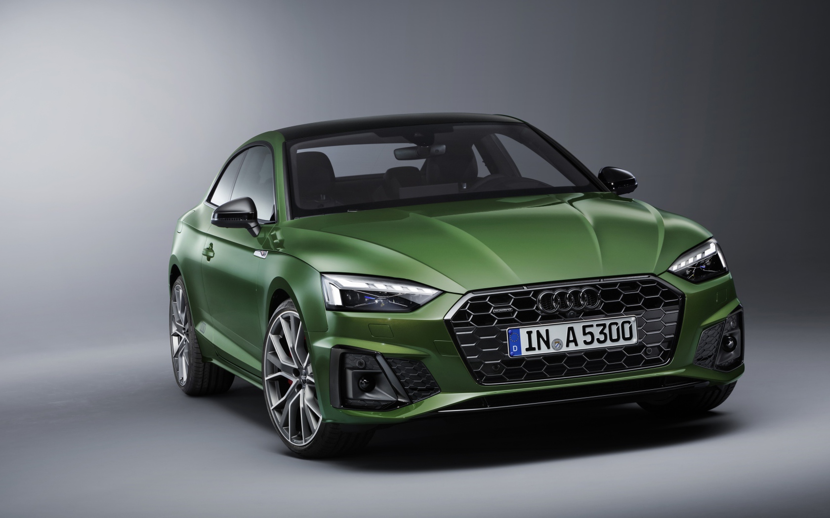 Зеленый автомобиль Audi A5 Coupe 40 TFSI Quattro S Line 2019 года на сером фоне