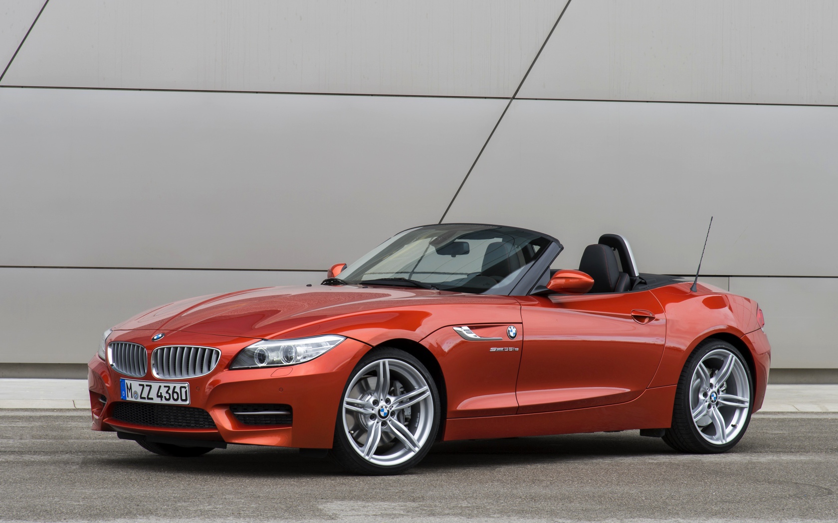 Оранжевый автомобиль кабриолет BMW Z4 на фоне стены