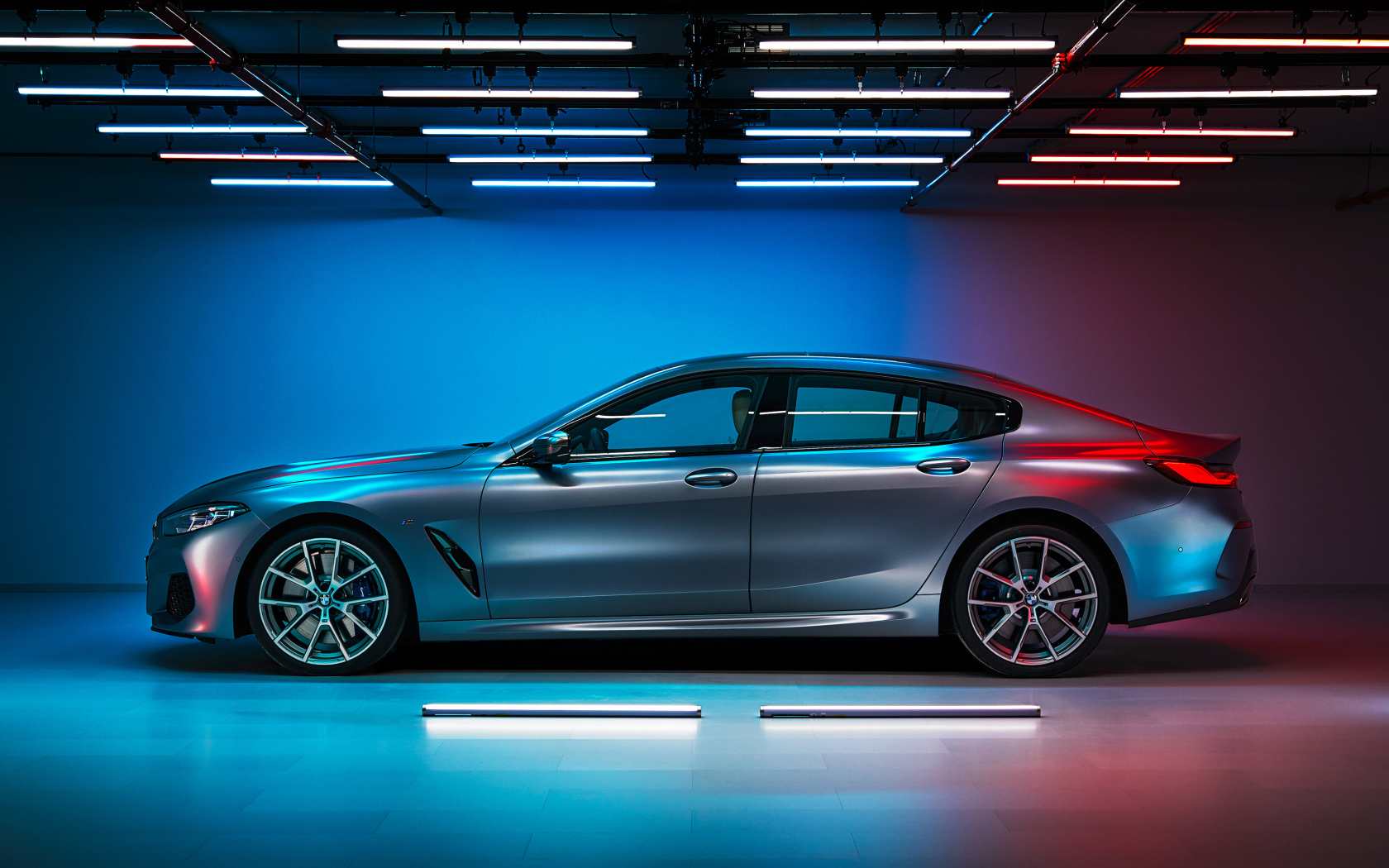 Серебристый автомобиль BMW M850i,  2019 года вид сбоку