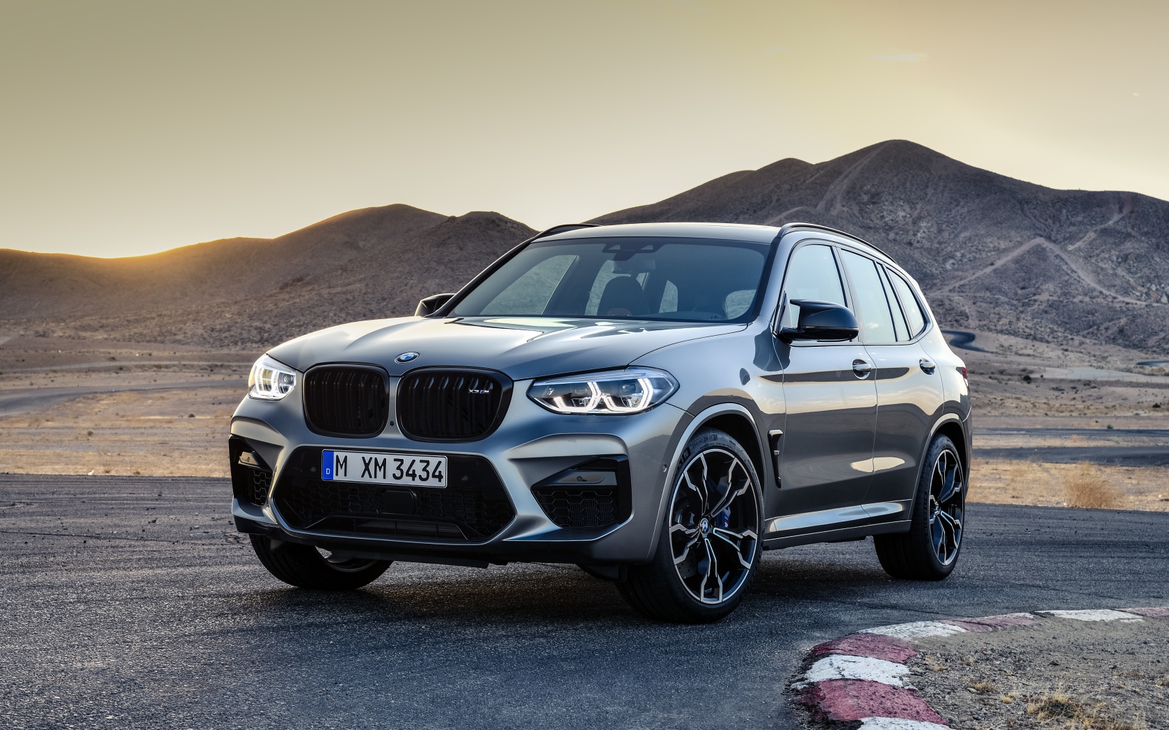 Серебристый автомобиль BMW X3  на асфальте
