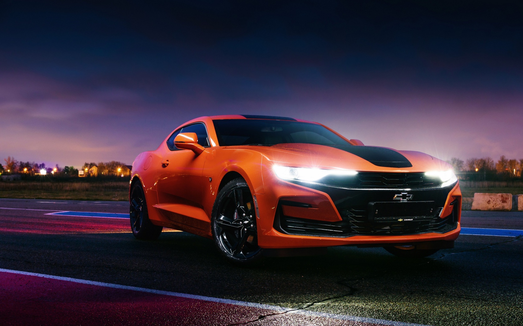 Оранжевый автомобиль Chevrolet Camaro, 2019 года с включенными фарами