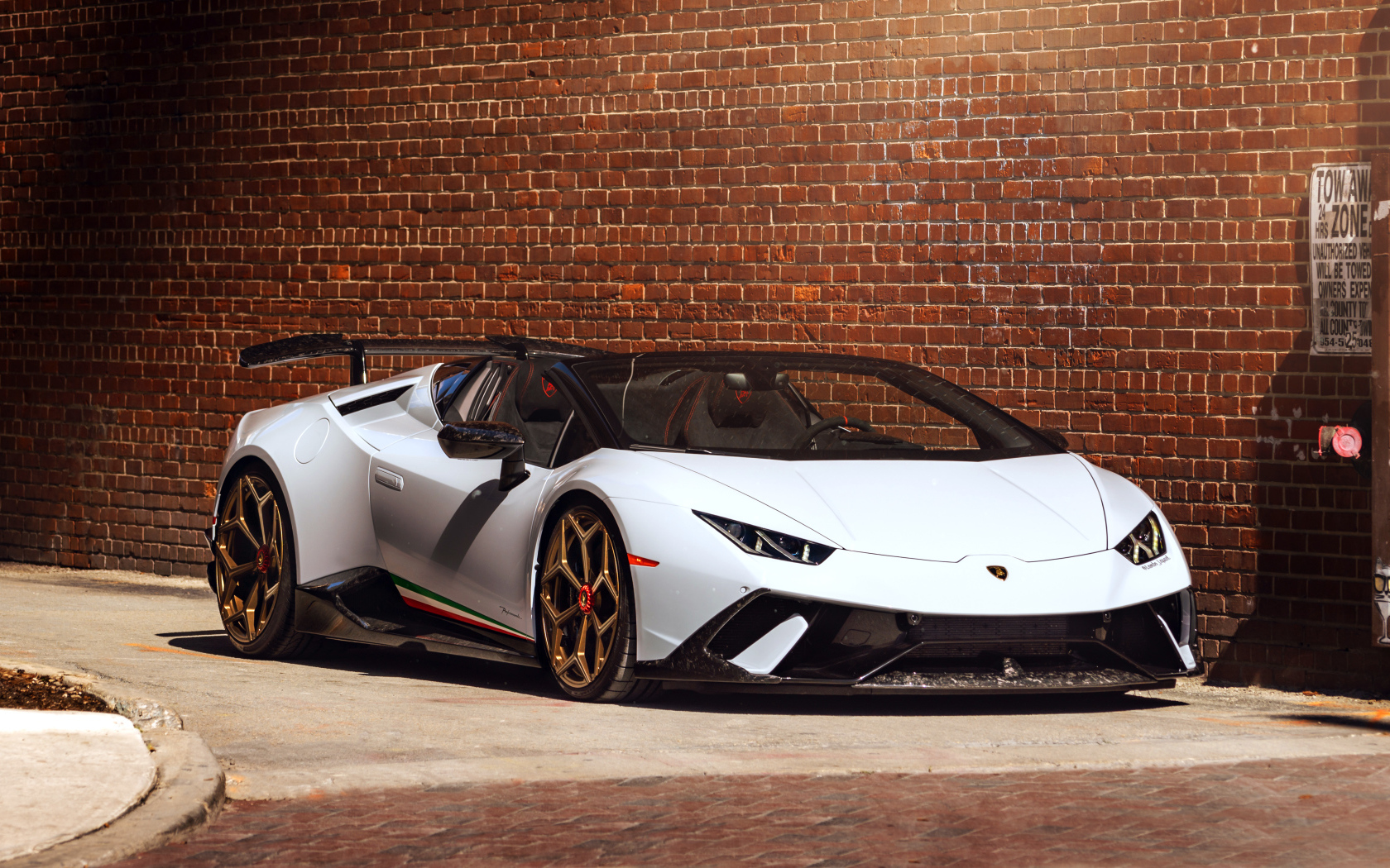 Белый быстрый Lamborghini Huracan стоит у кирпичной стены