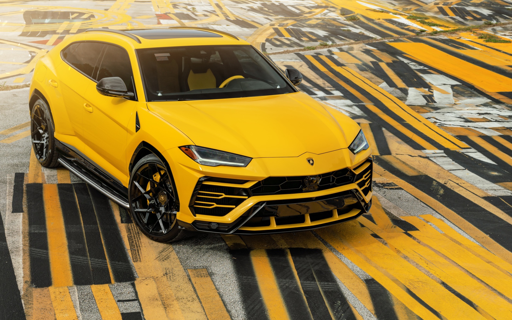 Желтый внедорожник Lamborghini Urus на разноцветном асфальте 