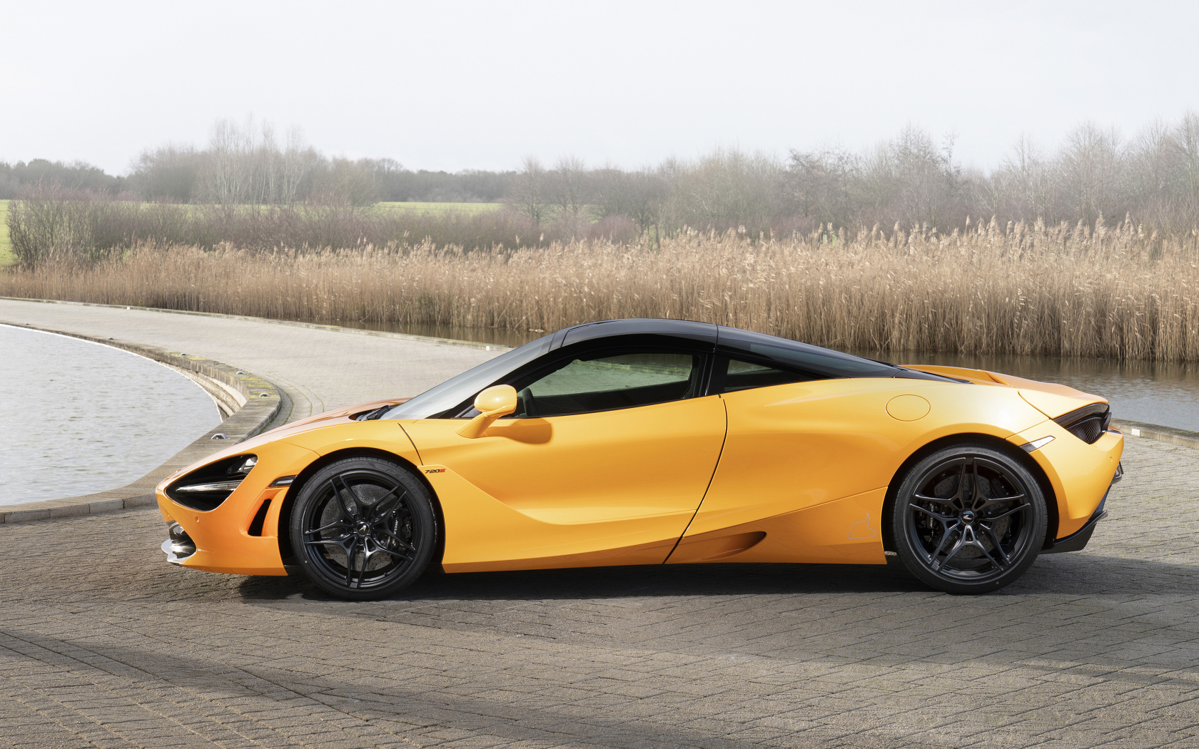 Желтый спортивный автомобиль McLaren MSO 720S Spa, 2019 года у воды