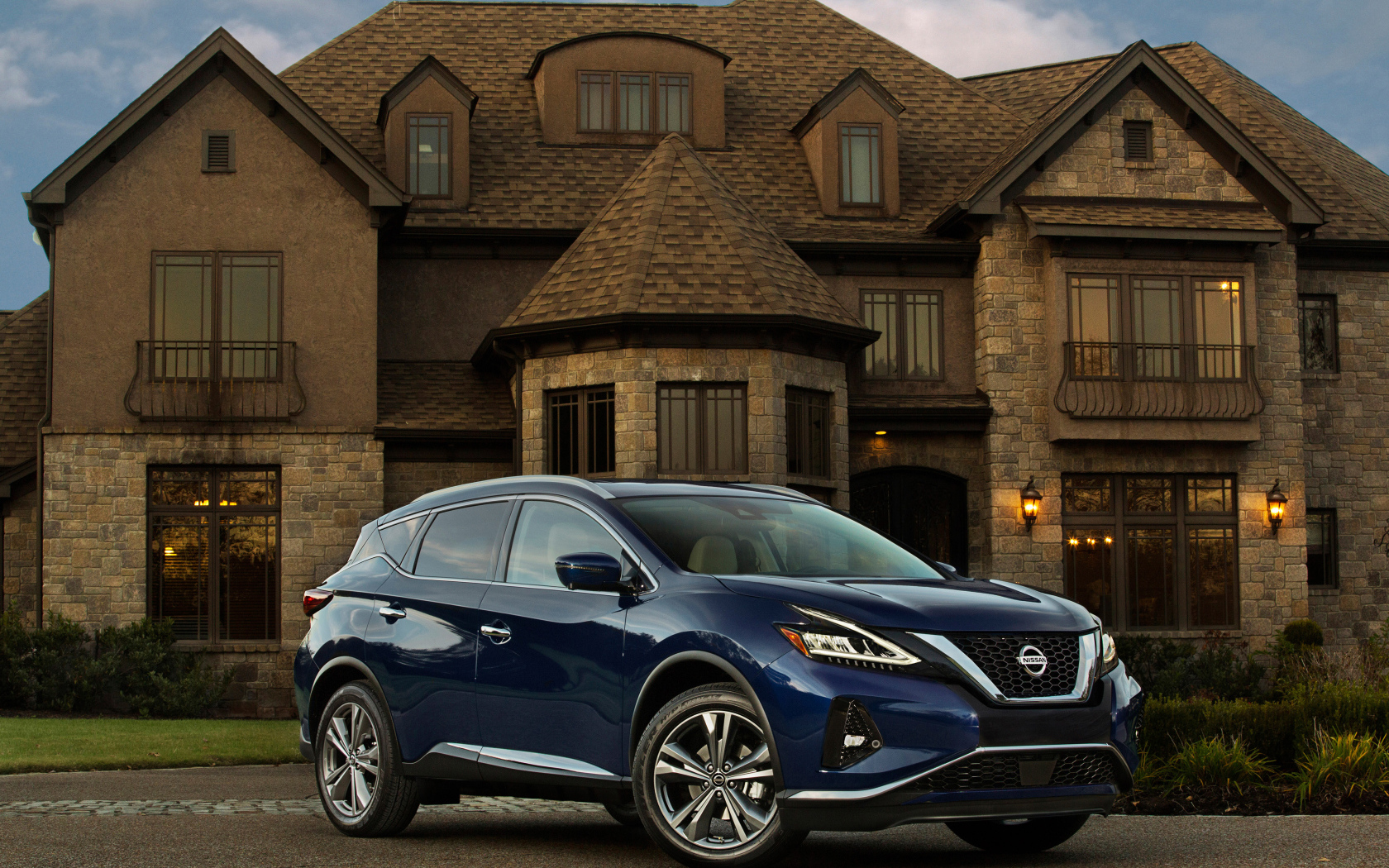 Синий автомобиль Nissan Murano на фоне особняка