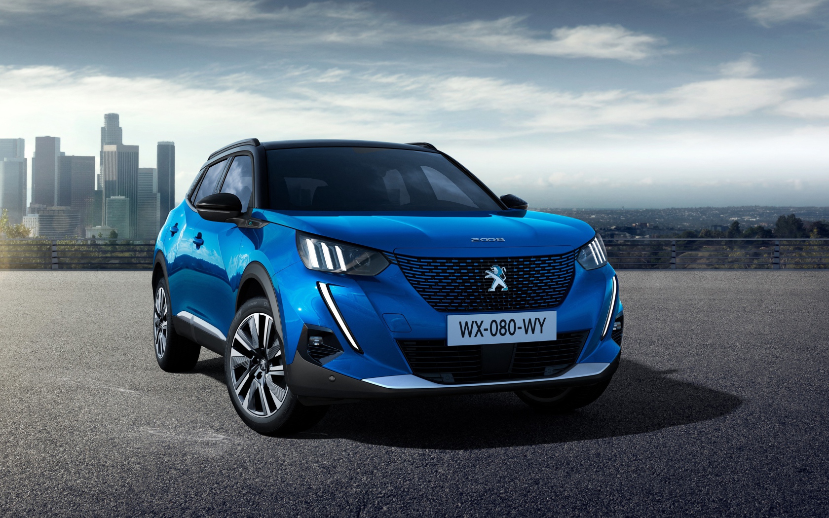 Синий внедорожник Peugeot E-2008 GT, 2019 года на фоне небоскребов