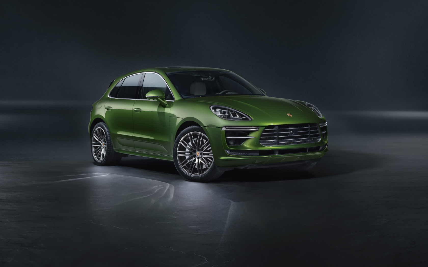 Зеленый автомобиль Porsche Macan Turbo 2019 года на сером фоне
