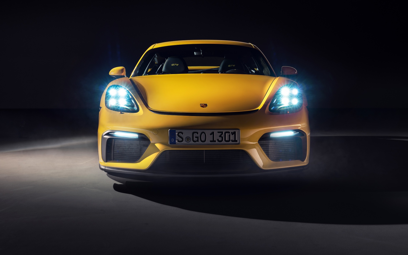 Автомобиль Porsche 718 Cayman GT4,  2019 года с включенными фарами 