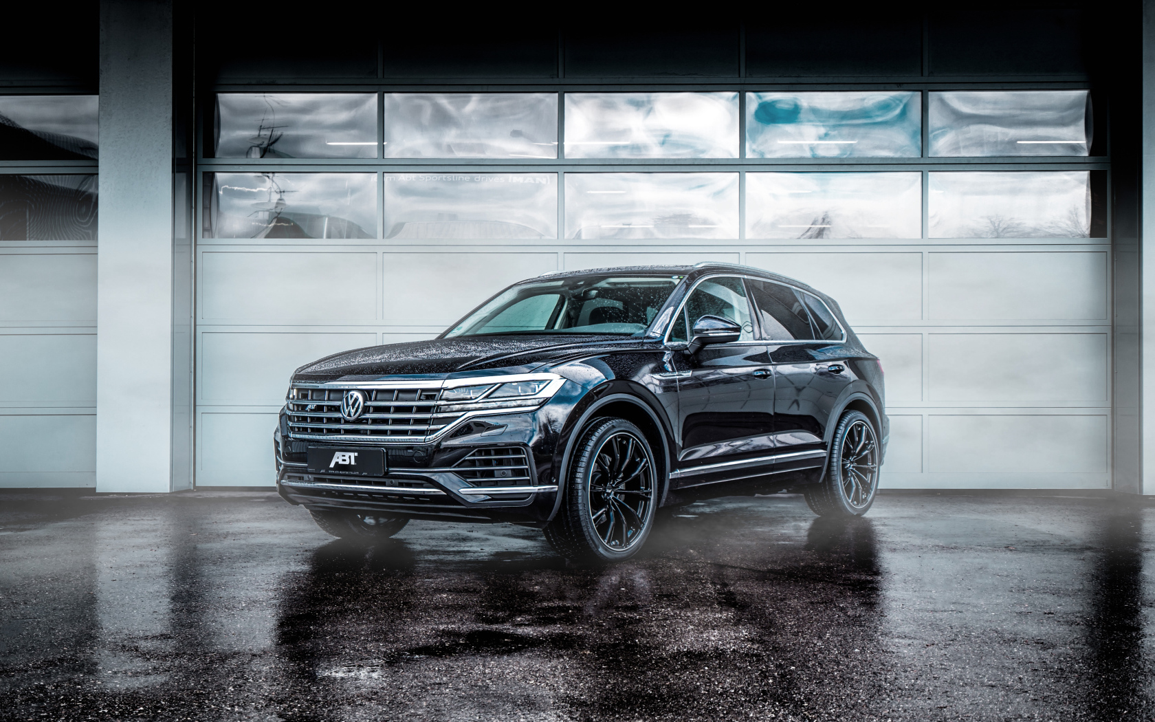 Черный автомобиль Volkswagen Touareg 2018 года у гаража