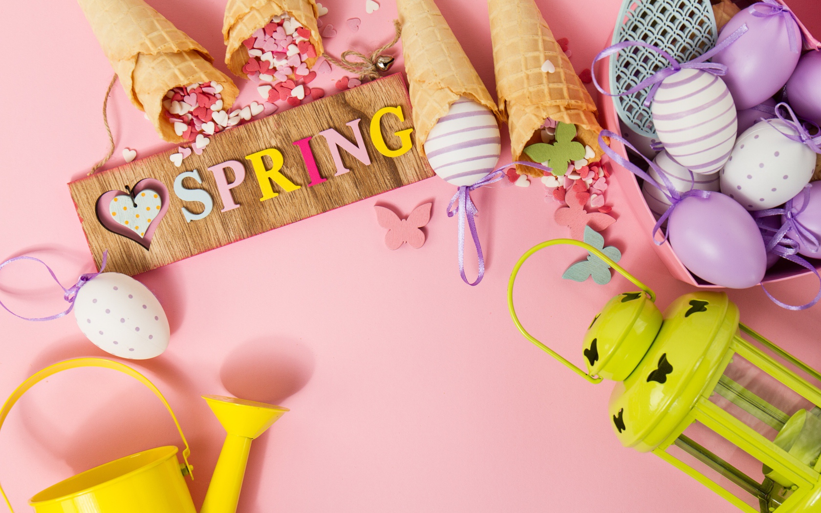 Надпись весна с вафельными рожками и яйцами на розовом фоне